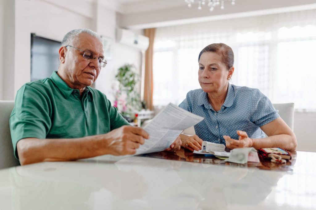 Senior couple sitting at a table looking at bills.