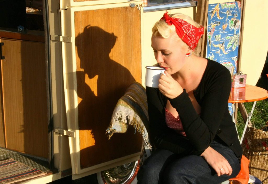 Woman sitting outside a caravan having a hot drink